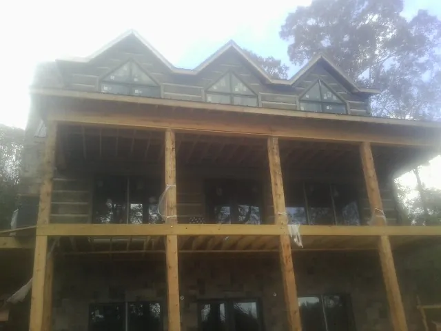 Dormers and porch framing on a large log home under construction — Roof Coating work by our crew in Elmira