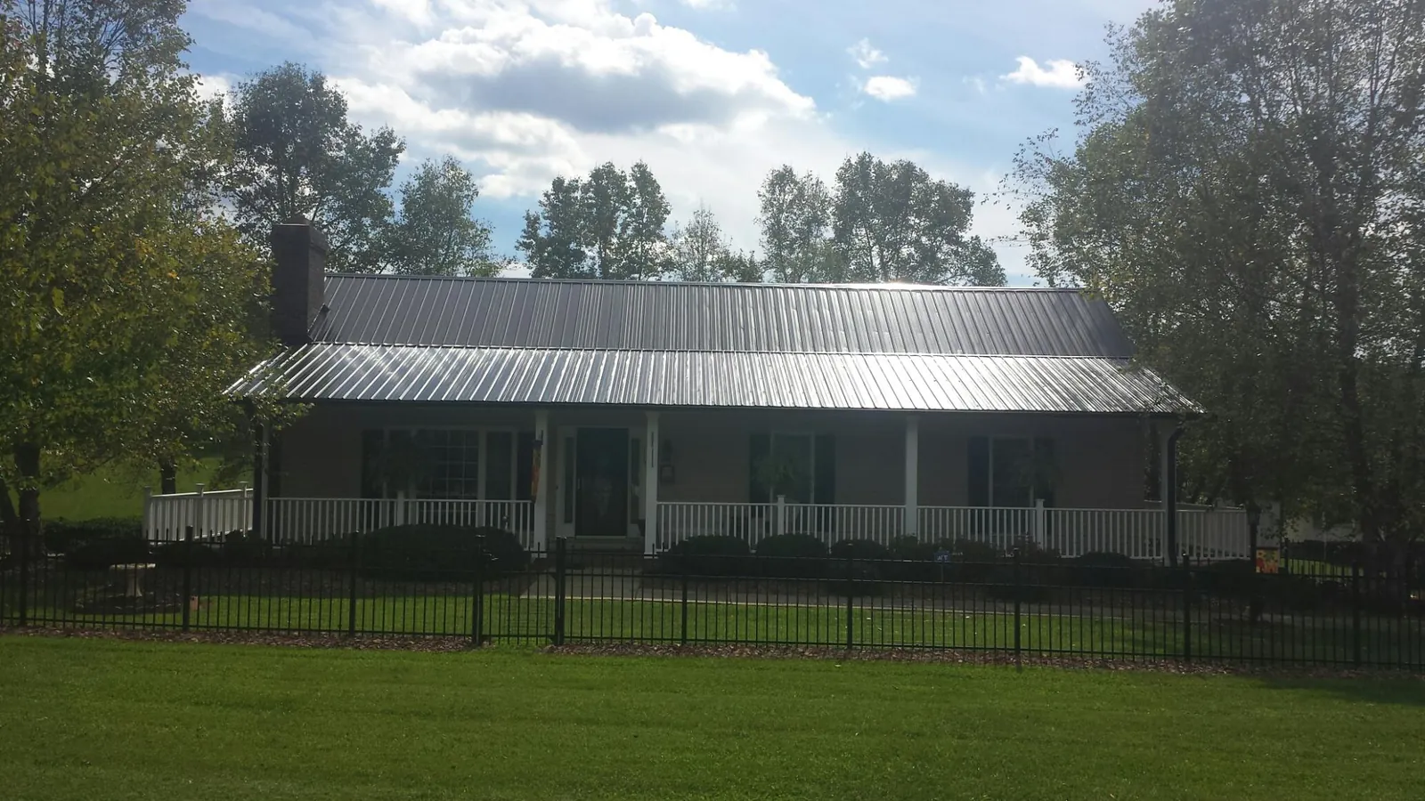 Gray metal roof on a brick ranch with a full width front porch — Gutter Guard Installation work by our crew in Elmira