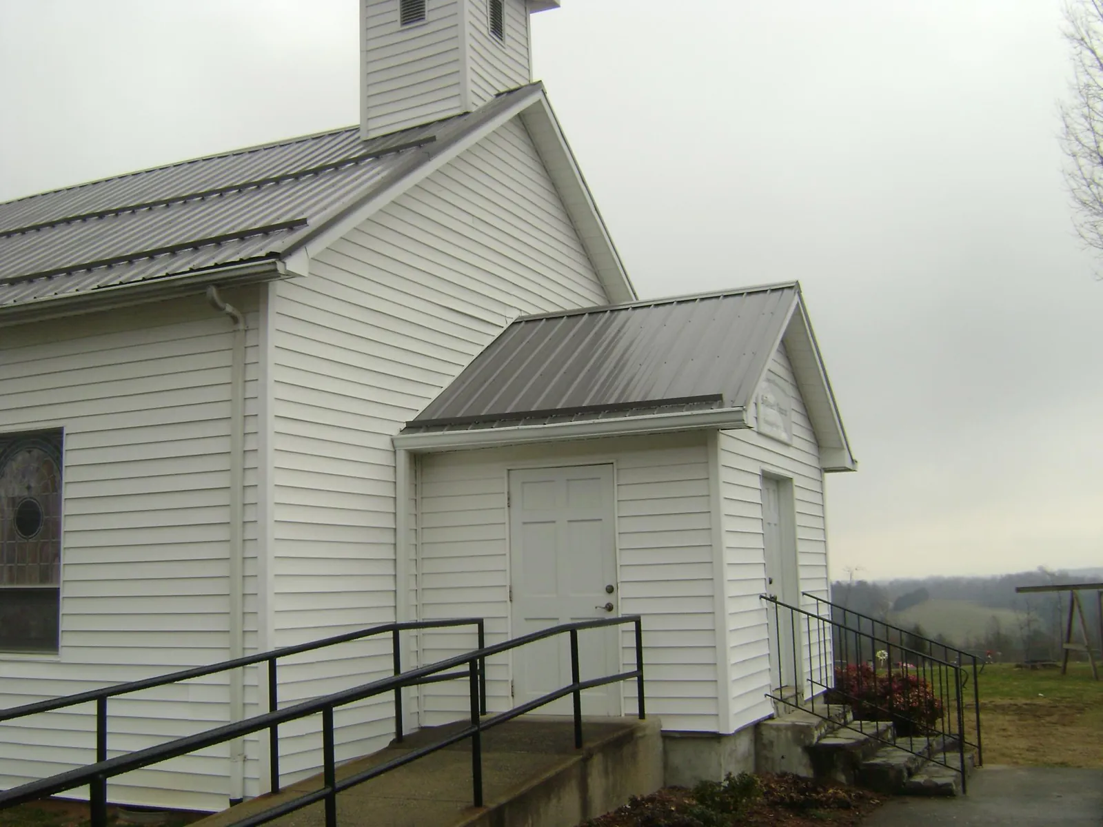 Gray metal roof on a white clapboard church with a steeple in Elmira
